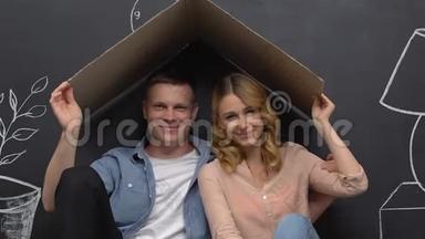 丈夫和妻子坐在纸板屋顶下，<strong>梦想</strong>着家，在一起